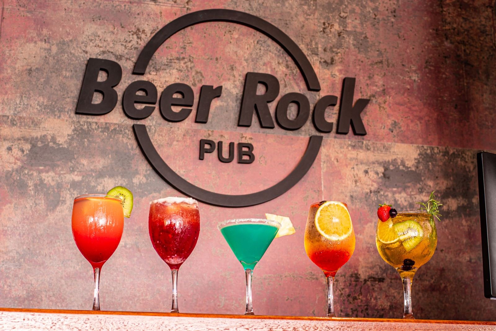Letreiro do Beer Rock Pub com três drinks no balcão em Porto de Galinhas