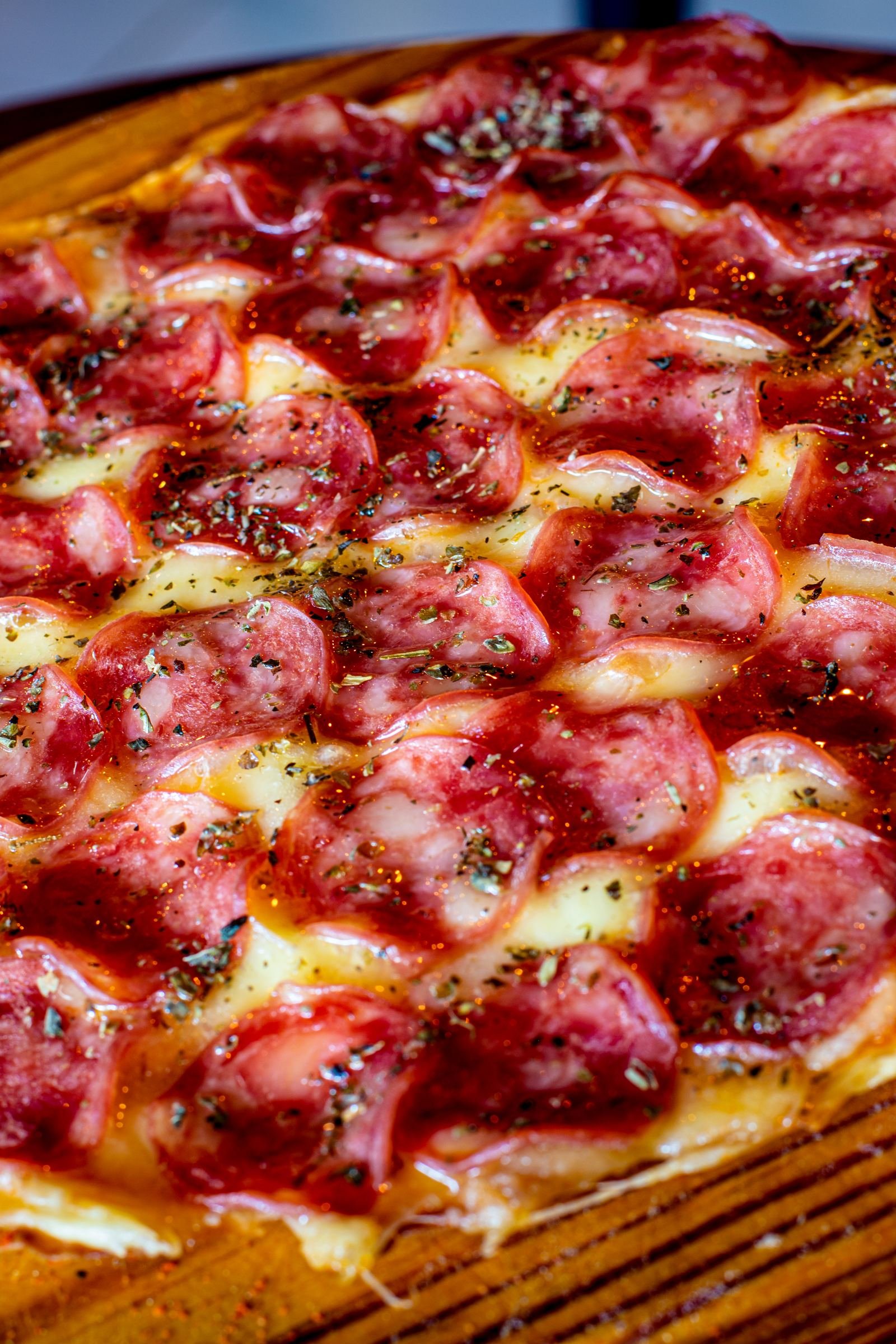 Pizza artesanal abundante en tabla de madera en el Beer Rock Pub en Porto de Galinhas